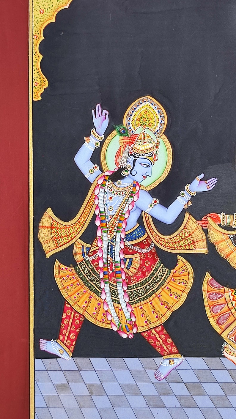 May include: A painting on a black background depicting a blue-skinned figure in a dynamic dancing pose. The figure wears an ornate gold crown, a yellow and red patterned skirt, and a long garland of pink lotus flowers over a bare chest.