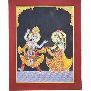 May include: A rectangular painting in a dark red frame depicting two figures dancing on a checkered floor against a black background. The blue-skinned figure wears a crown and yellow garments, while the other figure wears a green top and yellow skirt.