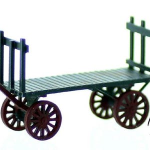 May include: A miniature wooden platform cart with a dark green wooden platform and four red wheels. The cart has a black metal frame with a vertical railing on the back.