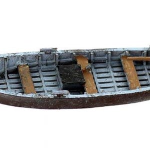 May include: A small wooden rowboat with a weathered gray paint finish and wooden oars. The boat is empty and ready for a day on the water.