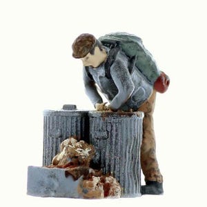May include: A miniature figurine of a person wearing a backpack and a cap, rummaging through two gray metal trash cans.