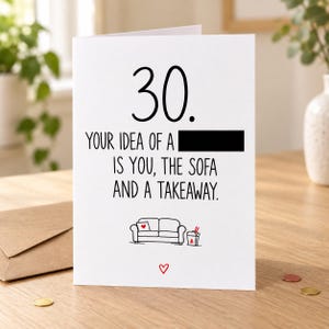 Lifestyle mock-up of a standing 30th birthday card with a sofa and takeaway doodle. One word in the joke is covered by a black bar. The card stands on a wooden table beside a kraft envelope and red/gold confetti.