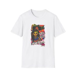 Puede incluir: Una camiseta blanca de manga corta con un estampado gráfico colorido de una persona con cabello oscuro, rodeada de salpicaduras de pintura abstractas. El texto dice: "YOU CAN DO ANYTHING. NOTHING IS FORBIDDEN." y "E.L. KIRCHNER. RAVE MUSEUM" en negro.