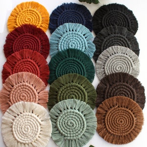 May include: Set of 12 round crocheted coasters with fringe in various colors, including red, blue, green, brown, beige, and white. The coasters are made with a spiral pattern and have a textured surface.