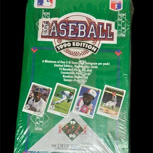 Könnte beinhalten: Versiegelte 1990 Upper Deck Baseball Kartenbox. Die grüne Box zeigt das MLB-Logo, die Worte "BASEBALL 1990 EDITION" und Bilder von Baseballkarten. Die Box ist in klarem Kunststoff verpackt.