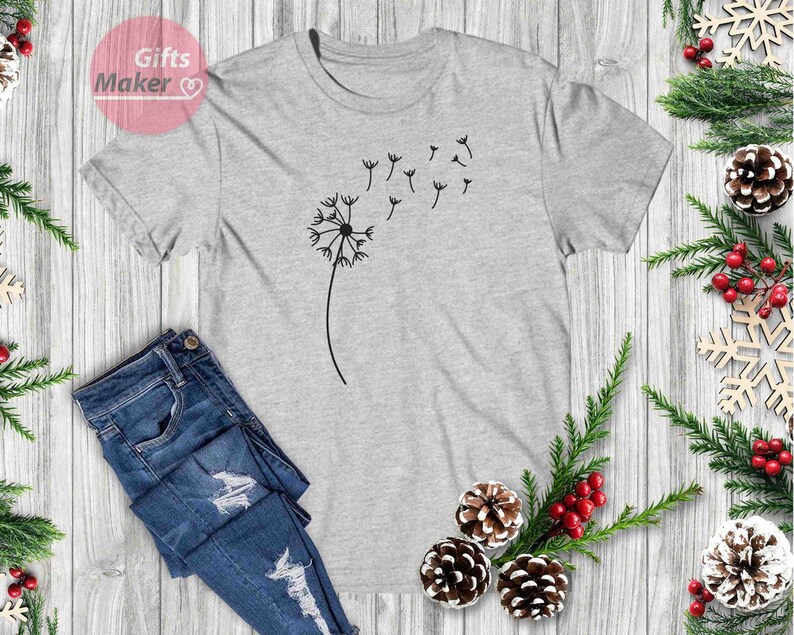 May include: A gray t-shirt with a black dandelion graphic. The dandelion is blowing in the wind and has seeds flying off of it.