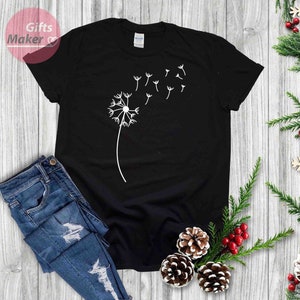 May include: A black t-shirt with a white dandelion design. The dandelion is blowing in the wind and has seeds floating away.