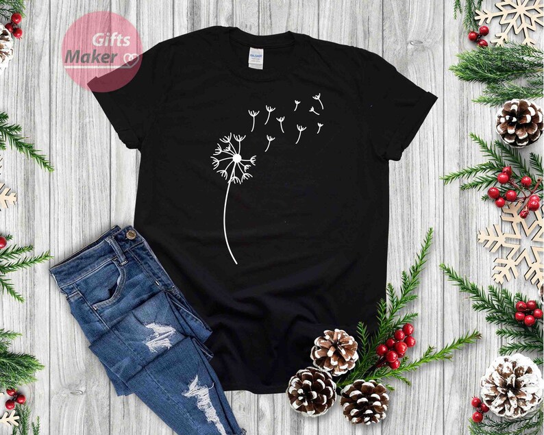 May include: A black t-shirt with a white dandelion design. The dandelion is blowing in the wind and has seeds floating away.