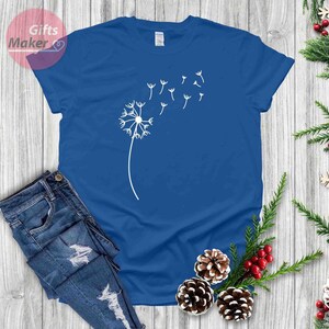 May include: A royal blue t-shirt with a white dandelion design. The dandelion has seeds blowing in the wind.