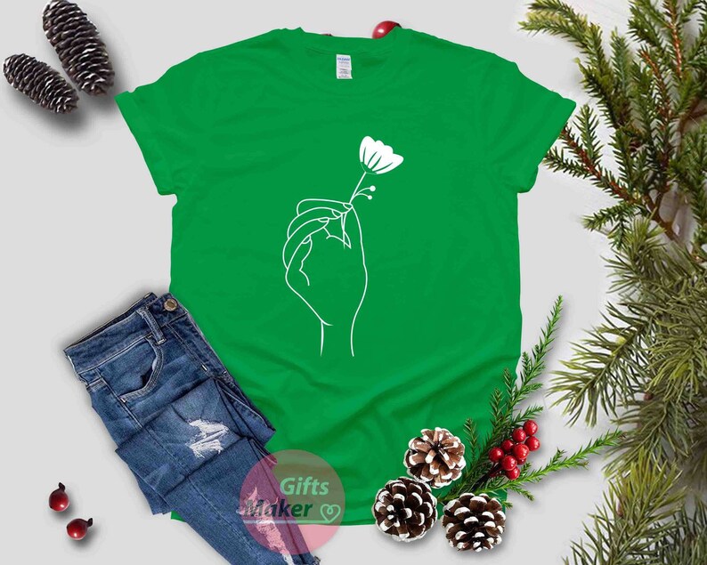 May include: A green t-shirt with a white outline of a hand holding a flower.