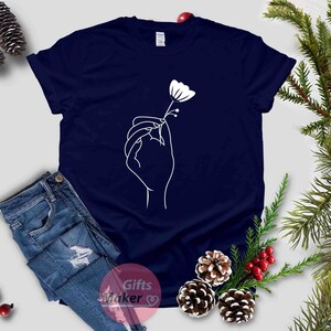 May include: A navy blue t-shirt with a white outline of a hand holding a flower.