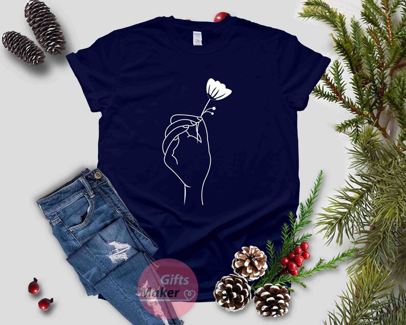 May include: A navy blue t-shirt with a white outline of a hand holding a flower.