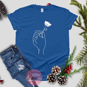 May include: A royal blue t-shirt with a white outline of a hand holding a flower.