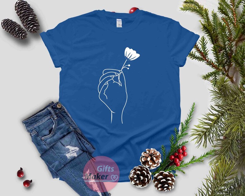 May include: A royal blue t-shirt with a white outline of a hand holding a flower.