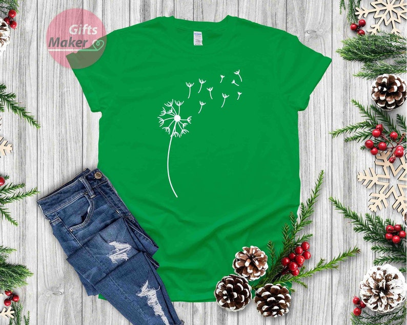 May include: A green t-shirt with a white dandelion graphic. The dandelion has seeds blowing in the wind.