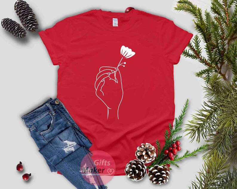 May include: A red t-shirt with a white outline of a hand holding a flower.