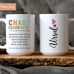 May include: Two white ceramic mugs. One mug has the text "Chaos Coordinator" with a definition and the text "See also: ninja, rockstar, legend". The other mug has the text "Ursula" with a red heart above the name.