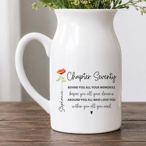 May include: A white ceramic pitcher with a handle, featuring a printed red poppy flower, the name Stephanie, and the text: Chapter Seventy, BEHIND YOU ALL YOUR MEMORIES, before you all your dreams, AROUND YOU ALL WHO LOVE YOU, within you all you need.