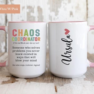 May include: White ceramic mug with a pink rim and handle. The mug features a black design that reads "Chaos Coordinator" with a definition and the name "Ursula" on the other side.