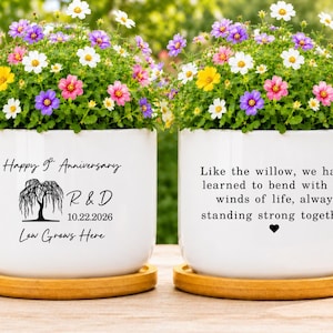 May include: Two white ceramic planters on bamboo saucers, filled with colorful flowers. One planter features a willow tree graphic, the text Happy 9th Anniversary, R & D, 10.22.2026, and Love Grows Here. The other displays the quote Like the willow, we have learned to bend with the winds of life, always standing strong together with a heart icon.