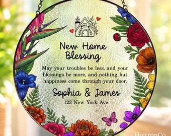 May include: A round glass suncatcher featuring a colorful floral border with red, orange, blue, and purple flowers. The center text reads New Home Blessing, a poem, the names Sophia & James, and the address 123 New York Ave, with a house icon.