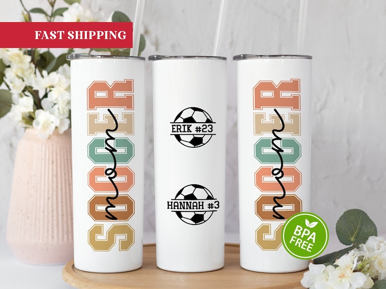 May include: Two white stainless steel tumblers with a colorful soccer mom design. The tumblers have a black soccer ball with the names Erik #23 and Hannah #3 on them. The tumblers are BPA free.