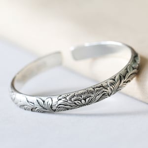 Crafted from 999 pure silver, this cuff bracelet features a beautifully hand-engraved peony design that symbolizes both beauty and strength. Its open-ended structure offers an adjustable fit,You can further personalize this bracelet by adding a custom engraving, creating a truly one-of-a-kind gift for mothers, wives, or daughters. Whether it's for Mother’s Day, birthdays, or anniversaries, this bracelet can be engraved with a meaningful message or name to make the occasion even more special.