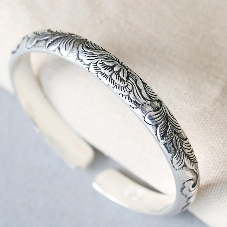 Crafted with care from 999 sterling silver, this cuff bracelet showcases a hand-engraved peony design that radiates beauty and strength. The open-ended design offers an adjustable fit, making it suitable for any wrist size. You can personalize it with your choice of engraving, adding a name, date, or special message that holds sentimental value. This customizable bracelet makes the perfect gift for Mother’s Day, birthdays, or anniversaries, and will be treasured for years to come.