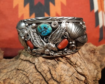May include: A silver bracelet with an eagle design and turquoise and coral stones.