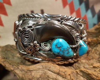 May include: A silver bracelet with a bear claw, turquoise stones, and intricate silverwork.