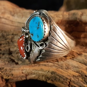 Könnte beinhalten: Ein silberner Ring mit Türkis- und Korallensteinen. Der Ring hat ein detailliertes Design mit einem fächerförmigen Muster auf der Band.