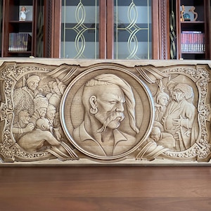 Op de afbeelding: Een gegraveerd houten paneel met een portret van een man met een snor en een vlecht in zijn haar. De man wordt omringd door andere figuren, allemaal gegraveerd in hout.
