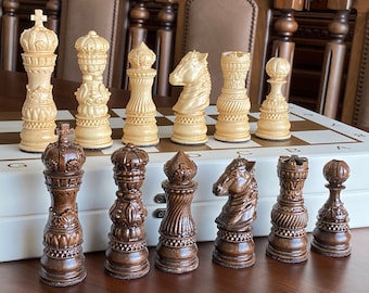 Può includere: Un set di pezzi degli scacchi con intagli intricati. I pezzi chiari sono fatti di legno chiaro e i pezzi scuri sono fatti di legno scuro. I pezzi sono disposti su una scacchiera.