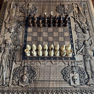 Op de afbeelding: Een houten schaakbord met ingewikkelde houtsnijwerk van ridders en andere figuren. Het bord is gemaakt van donker hout en heeft een lichtbruin schaakbordpatroon. De schaakstukken zijn in de beginpositie gerangschikt.