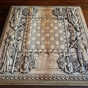Op de afbeelding: Een houten schaakbord met ingewikkelde houtsnijwerk van ridders, dames en wapenschilden. Het bord is gemaakt van licht hout en heeft een donkerbruine vlek. Het schaakbord is omgeven door een decoratieve rand.