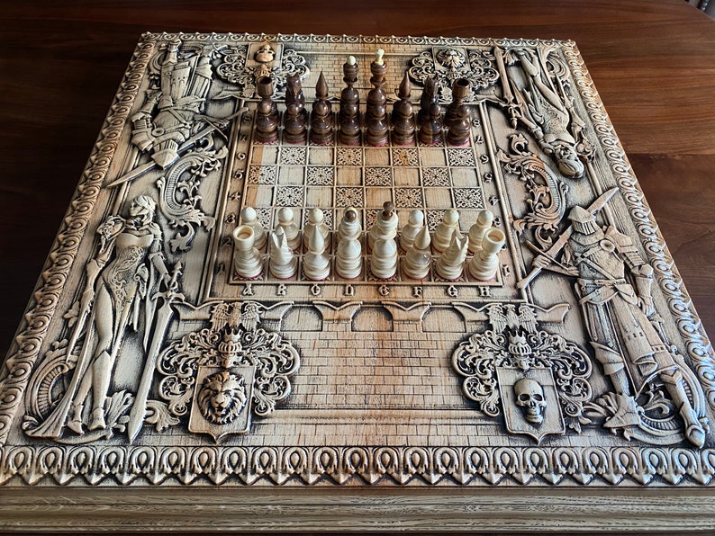 Op de afbeelding: Een houten schaakbord met ingewikkelde houtsnijwerk van ridders en andere figuren. Het bord is gemaakt van licht hout en heeft een donkerbruine vlek. De schaakstukken zijn gemaakt van wit en bruin hout en zijn gerangschikt in hun startposities.