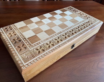 May include: A wooden chessboard with a carved, ornate border. The board is closed and has a latch.