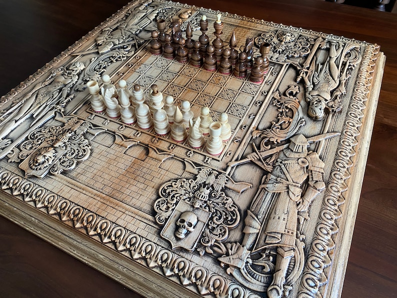 Op de afbeelding: Een houten schaakbord met ingewikkelde houtsnijwerk van ridders, draken en andere mythische wezens. Het bord is gemaakt van licht hout en heeft een donkerbruine vlek. De schaakstukken zijn gemaakt van wit en bruin hout en staan in de beginpositie op het bord.