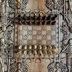 Op de afbeelding: Een houten schaakbord met ingewikkelde houtsnijwerk van ridders en andere figuren. Het bord is opgezet voor een potje schaken met de stukken in hun beginposities. Het bord is gemaakt van licht hout met donkere houten vierkanten.