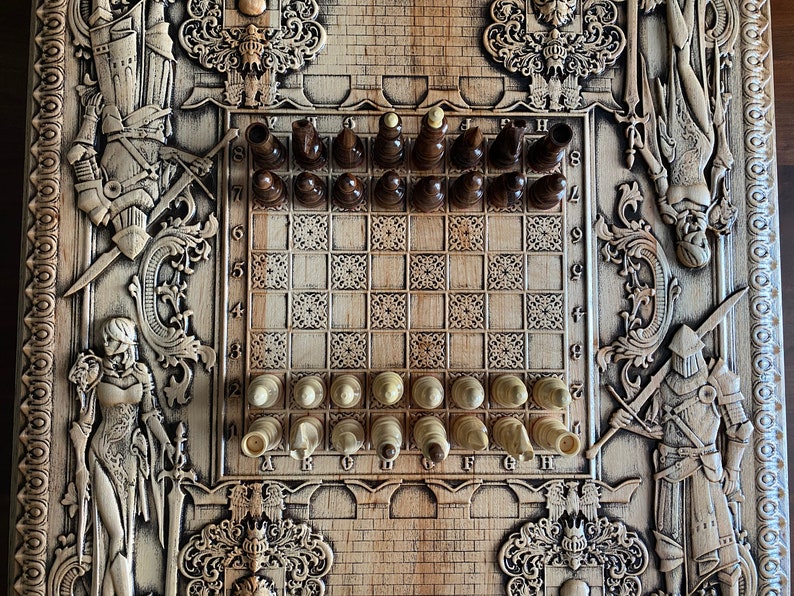 Op de afbeelding: Een houten schaakbord met ingewikkelde houtsnijwerk van ridders en andere figuren. Het bord is opgezet voor een potje schaken met de stukken in hun beginposities. Het bord is gemaakt van licht hout met donkere houten vierkanten.