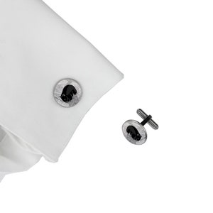 Peut inclure: Une paire de boutons de manchette en argent avec un motif d'ours noir. Les boutons de manchette sont ronds et ont une surface texturée.