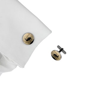 Peut inclure: Une paire de boutons de manchette en argent avec un motif rond de couleur or représentant une silhouette noire d'émeu.