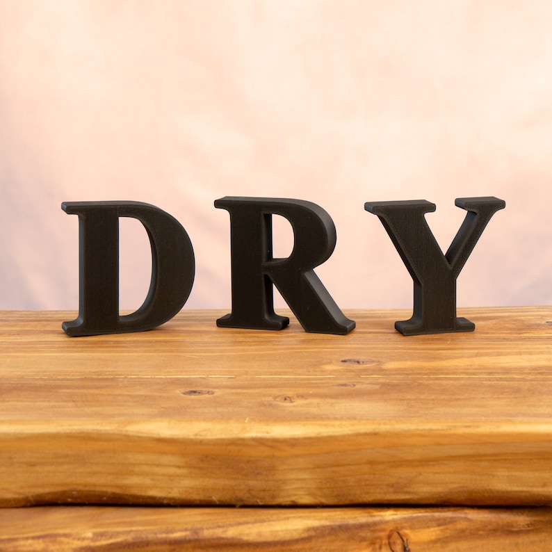 May include: Black wooden letters spelling out the word "DRY" on a wooden surface.