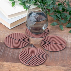 May include: Four brown and black striped round coasters with a glass of water on top of one of the coasters.
