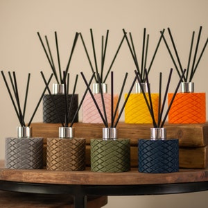 May include: Eight diffuser bottles with black reeds, each bottle has a different colour and a textured design. The colours are grey, brown, green, blue, black, pink, yellow, and orange.