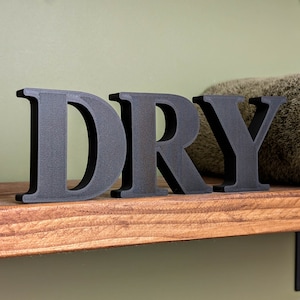May include: Black wooden letters spelling "DRY" on a wooden shelf.