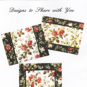 May include: Three placemats with a floral design featuring black borders and a white background with red roses. The placemats are 13 inches by 17 inches. The text "As You Like It" is printed below the placemats. The text "#211" is printed below the text.