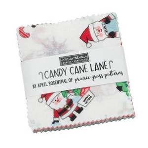 May include: A stack of fabric squares with a Christmas theme. The fabric features Santa Claus, candy canes, and Christmas trees on a white background. The text "CANDY CANE LANE" is printed on a white band wrapped around the fabric squares.