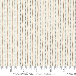 May include: A cream-colored fabric featuring a repeating pattern of thin vertical stripes in alternating shades of dark gray and burnt orange. A white ruler is visible at the bottom, showing a scale of 6 inches for size reference.