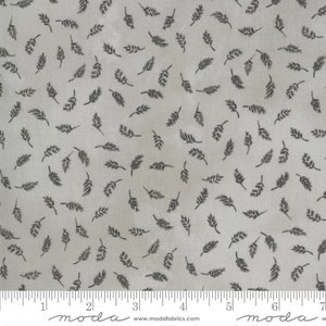 May include: A gray fabric with a repeating pattern of small black leaves. The fabric is measured with a ruler in inches. The text "moda" is printed on the ruler.